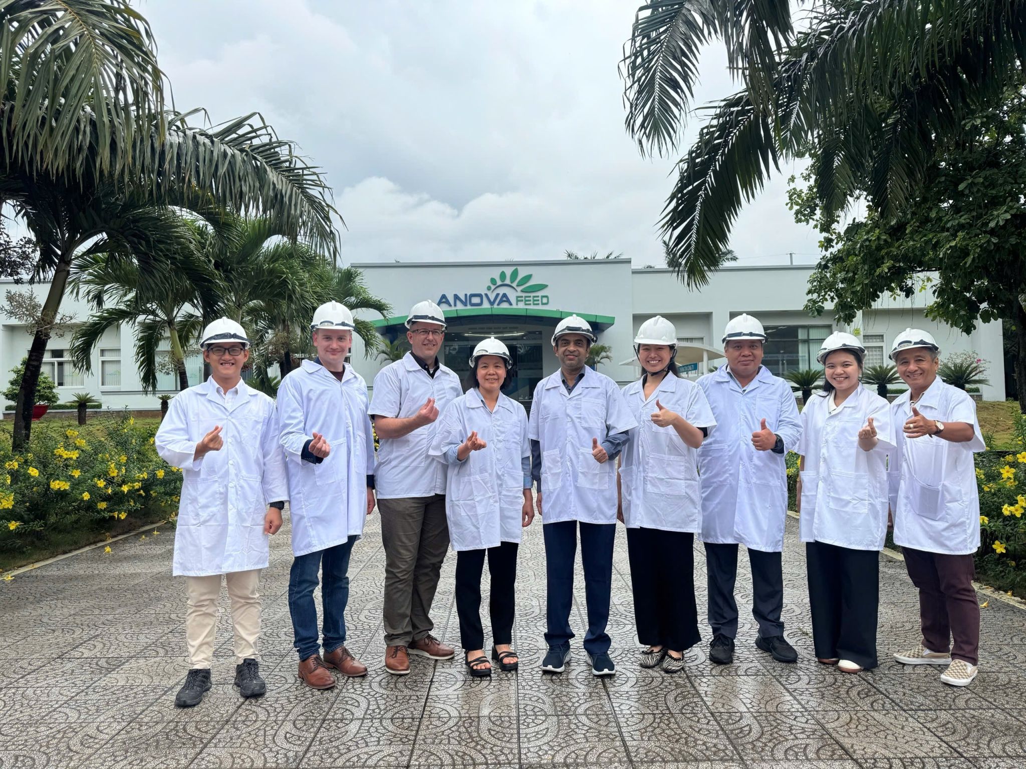 IABC staff and Wisconsin company reps in lab coats stand in front of Anoya Feed building.