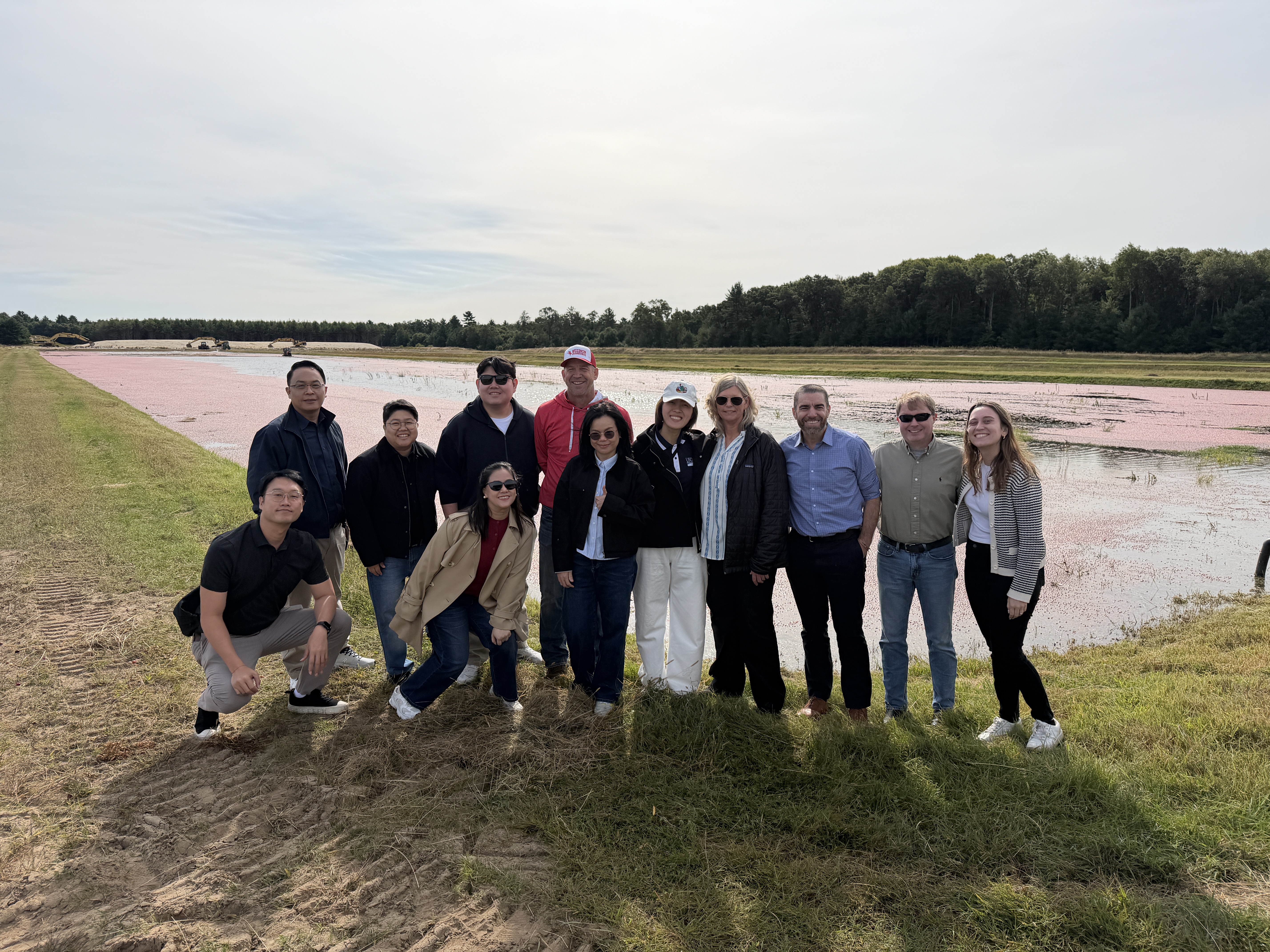 Mission participants and IABC staff pose in front of a cranberry marsh.