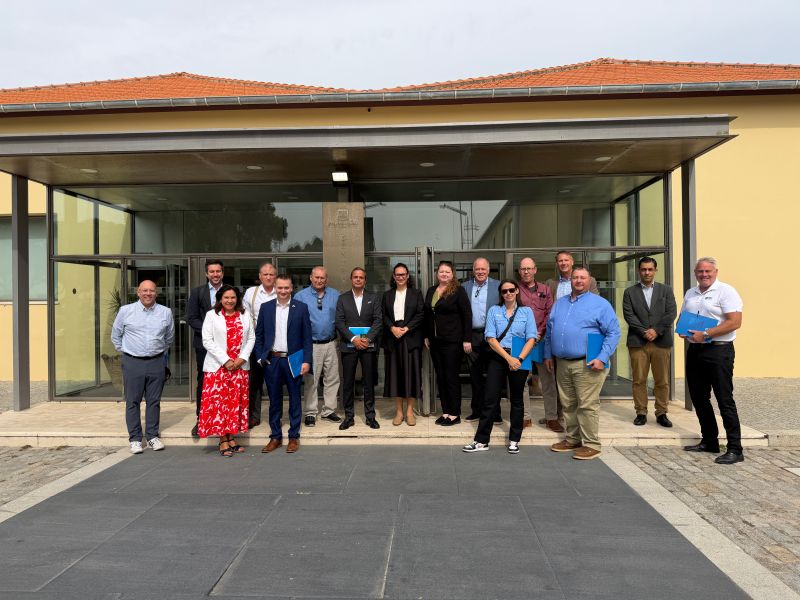 The mission group smile in front of a modern building on a cloudy day.