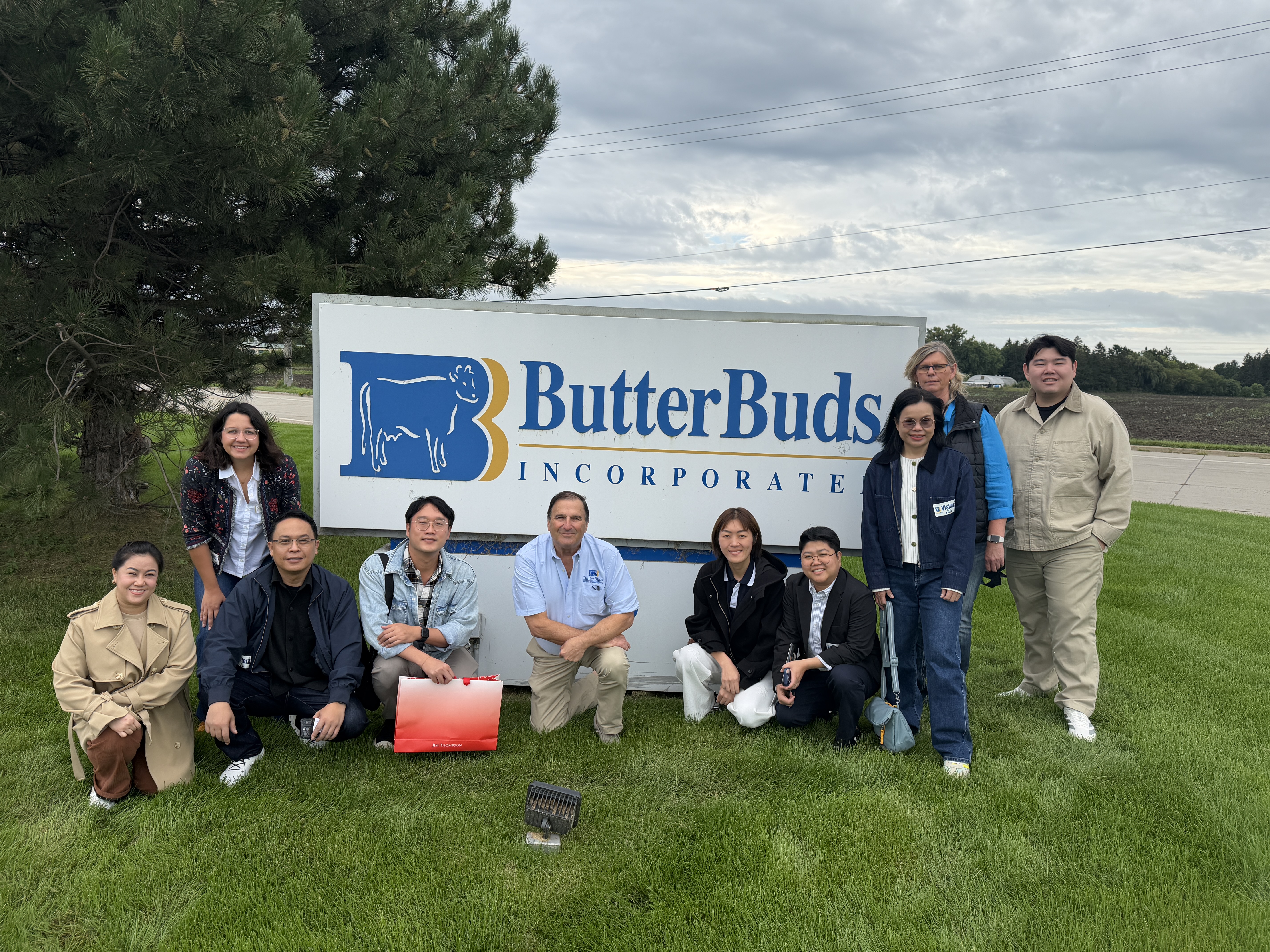Mission members and IABC staff  pose in front of the ButterBuds Incorporate sign.