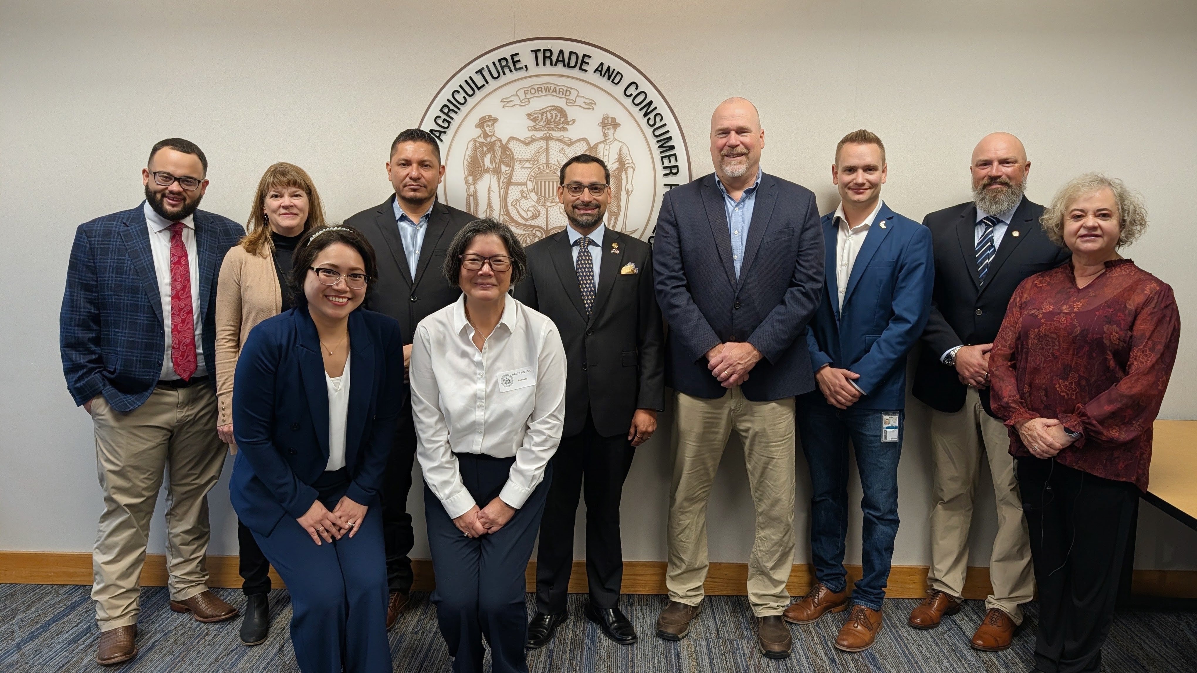 Panamanian reps and DATCP reps smile in front of DATCP logo.