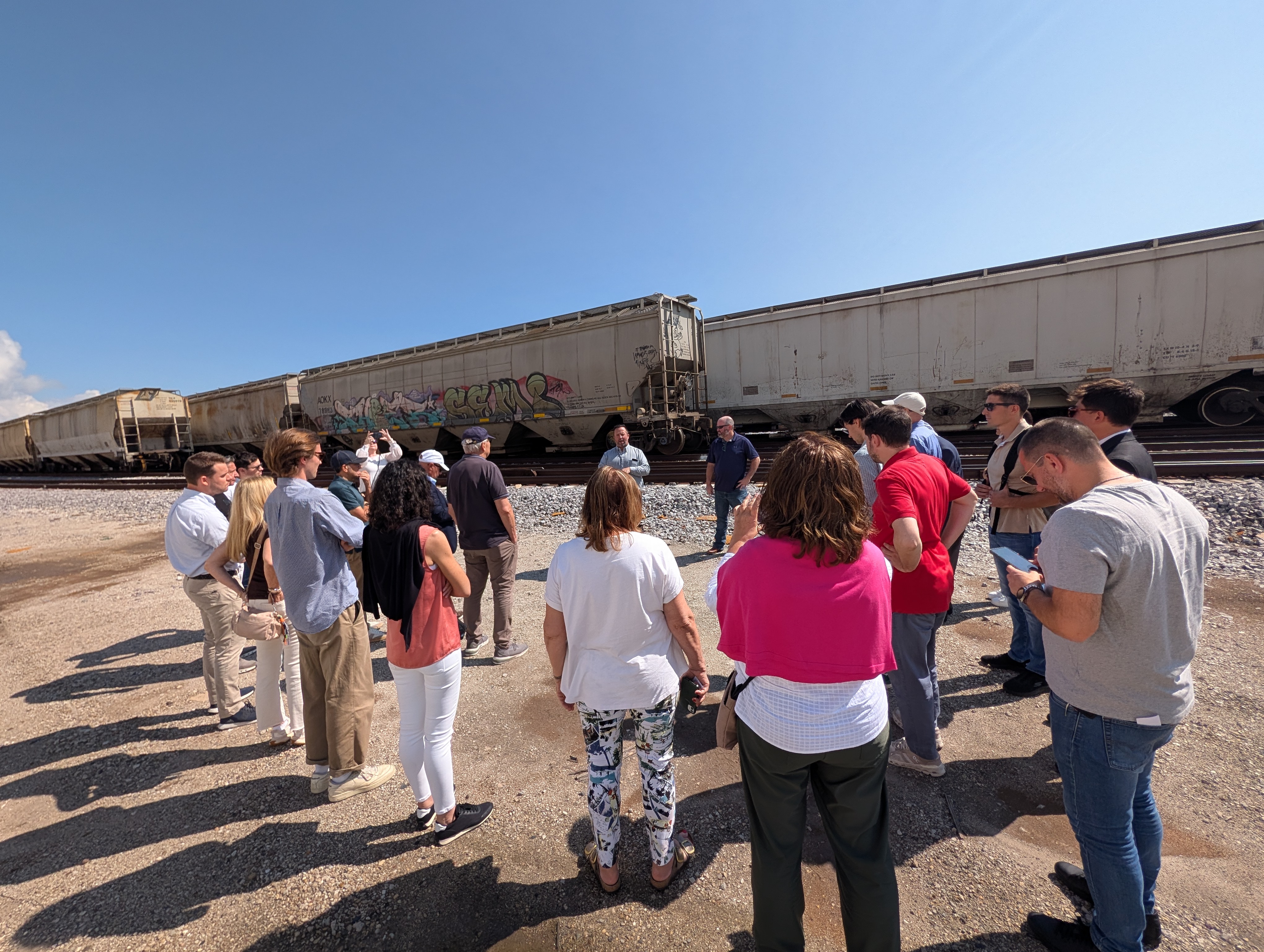 A group stands in a circle near a train.