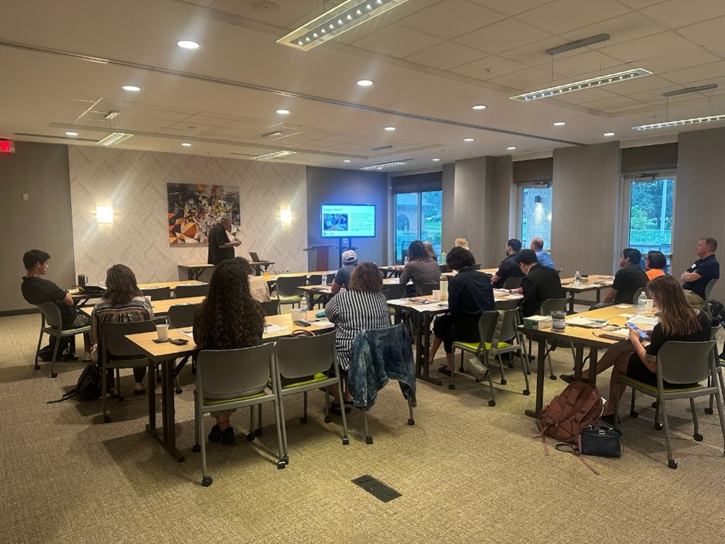 People watch a presentation seated in rows in a room.