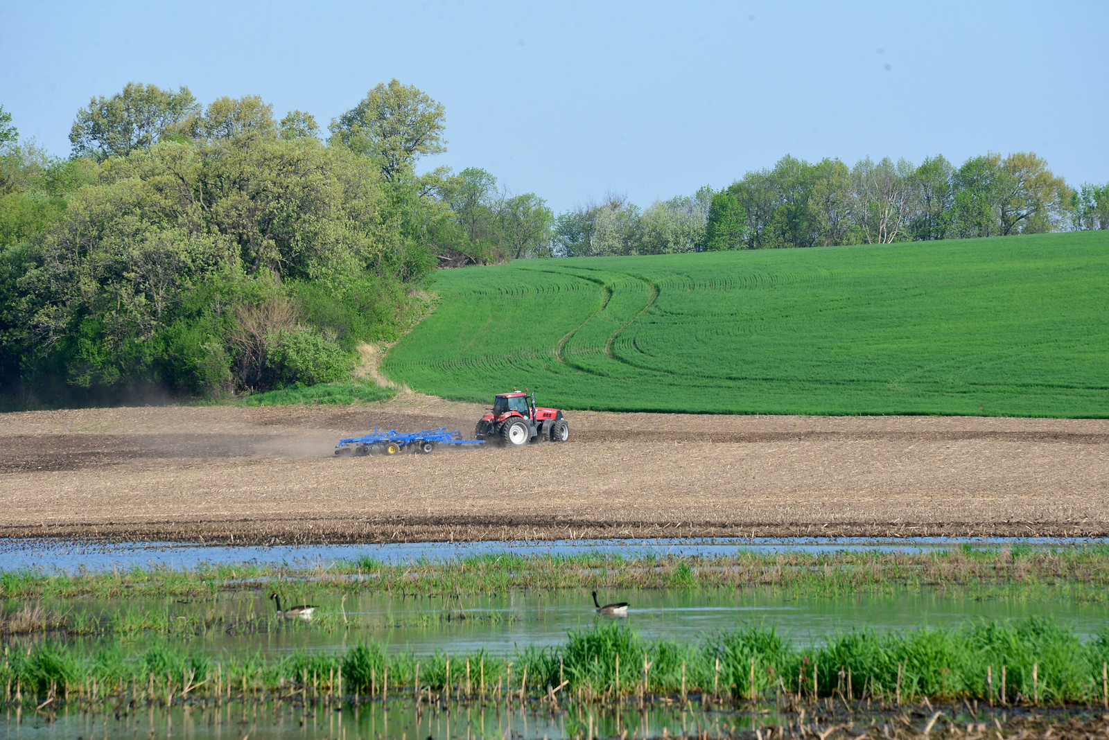 tractor in field with pond in foreground